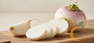 “Nabo fresco cortado em fatias sobre tábua de madeira.”